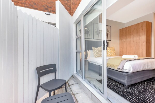 A bedroom with a bed, a chair, and a sliding glass door leading to a balcony.