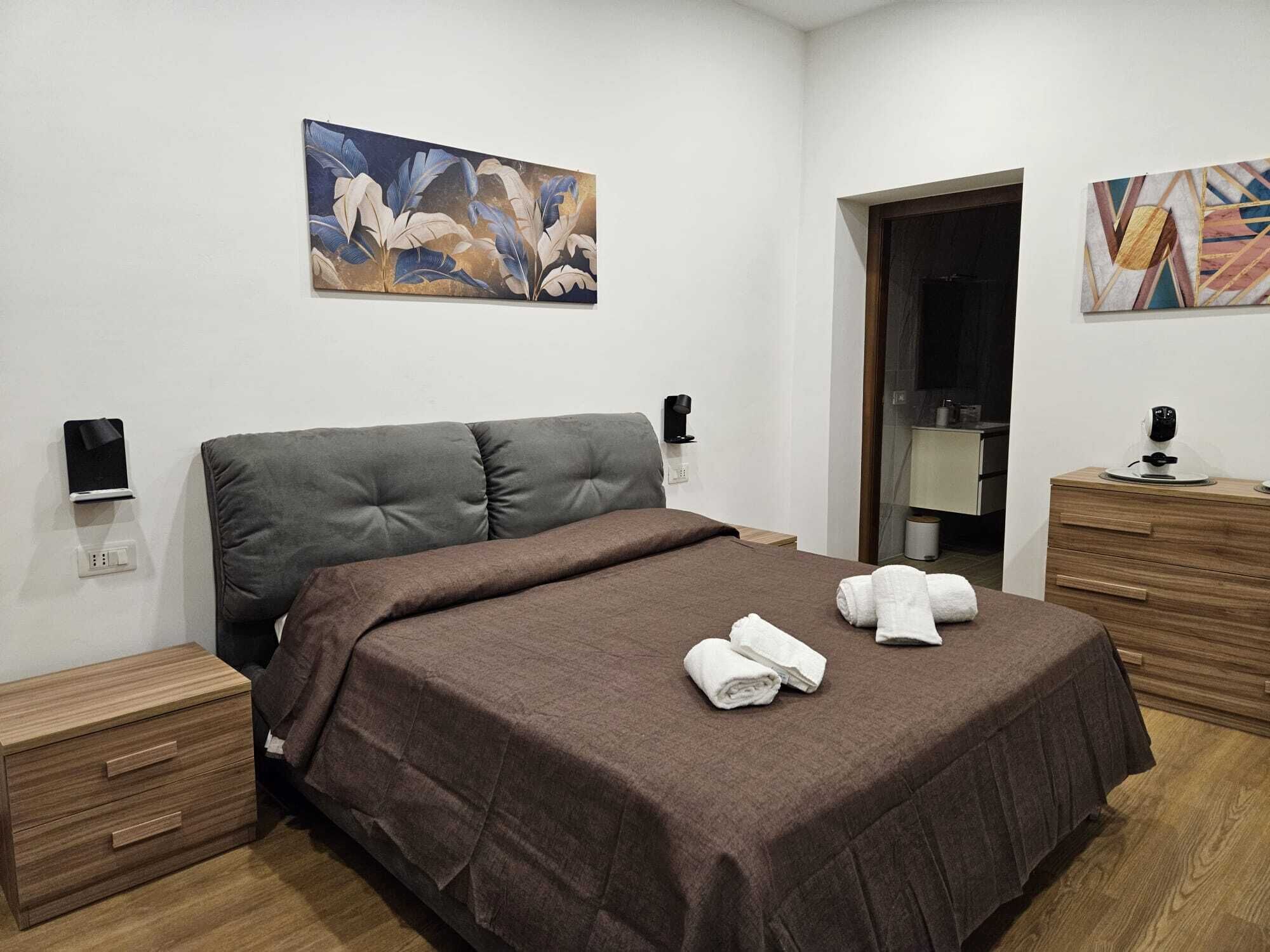 Una habitación de hotel moderna con una cama grande, una mesita de noche, un espejo y obras de arte en las paredes.