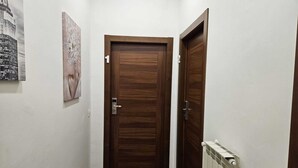 A hallway with a wooden door, a radiator, and a framed picture on the wall. - La Darsena Guesthouse (Civitavecchia)