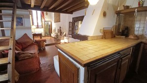 A rustic kitchen with a wooden island, a dining area with a red sofa, and a hallway leading to another room. - Loft in the heart of Nice (Nice)