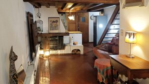 A cozy living room with a wooden staircase, a fireplace, and a dining area with a table and chairs. - Loft in the heart of Nice (Nice)