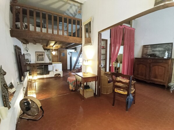 A spacious living room with a high ceiling, a wooden staircase, and a cozy seating area with a table and chairs.