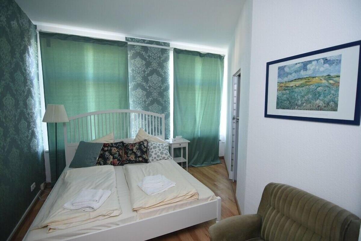 A bedroom with a bed, a chair, and a painting on the wall.