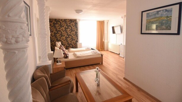 Een hotelkamer met een bed, een bank, een bijzettafeltje en een schilderij aan de muur.