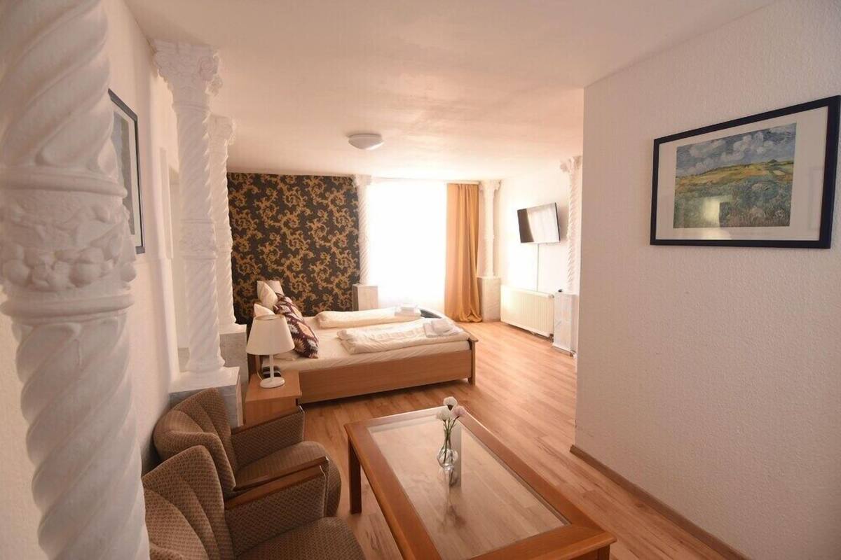 A hotel room with a bed, a sofa, a coffee table, and a painting on the wall.