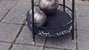Een metalen tafel met een bloempot en decoratieve bolvormen.