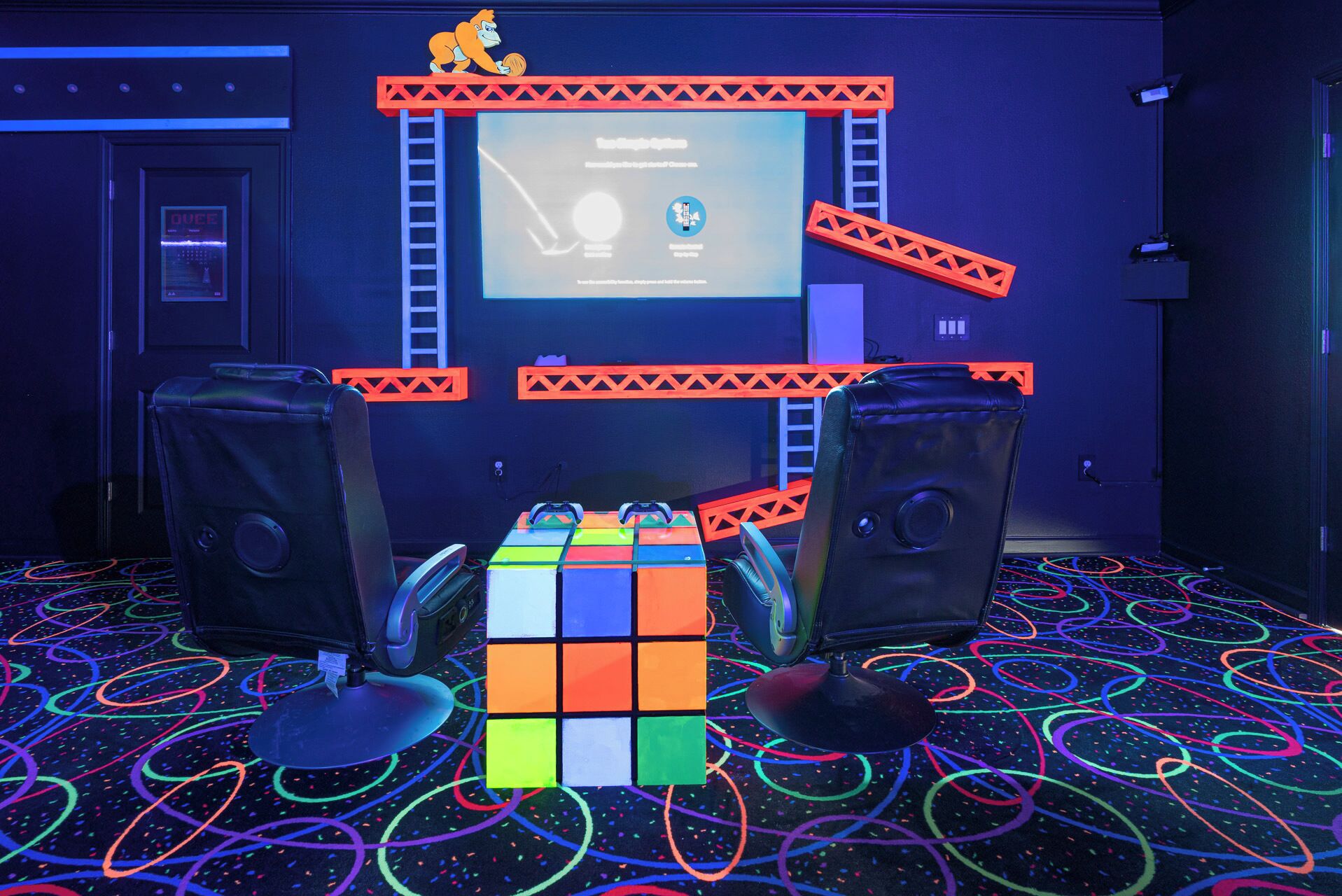 A room with a Rubik's Cube, two speakers, and a screen displaying a presentation.