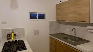 A modern kitchen with a white countertop, wooden cabinets, a gas stove, and a hanging light fixture.