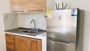 A kitchen with wooden cabinets, a stainless steel refrigerator, and a marble countertop.