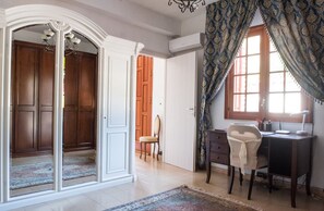 A room with a desk, chair, and a large window with curtains. There is a door leading to another room and a chandelier. - Villa Blondie in Castellammare del Golfo (Castellammare del Golfo)