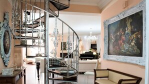 A spacious living room with a curved staircase, a grand piano, and a large classical painting. - Villa Blondie in Castellammare del Golfo (Castellammare del Golfo)