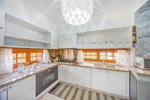 A kitchen with white cabinets, a stove, a sink, and a microwave.