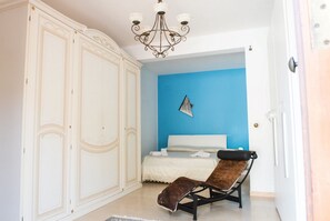 A bedroom with a blue accent wall, a bed, a chair, and a wardrobe.