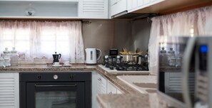 A kitchen with a gas stove, a coffee maker, and a kettle. There are cabinets and a countertop. - Villa Blondie in Castellammare del Golfo (Castellammare del Golfo)