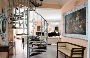 A spacious living room with a curved staircase, a grand piano, and a large classical painting. - Villa Blondie in Castellammare del Golfo (Castellammare del Golfo)