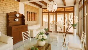 A modern living room with a glass coffee table, white furniture, a brick wall, and large windows. - Villa Blondie in Castellammare del Golfo (Castellammare del Golfo)