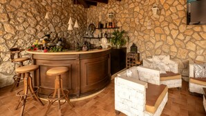 A stone-walled bar area with stools, a bar counter, and wicker furniture. - Villa Blondie in Castellammare del Golfo (Castellammare del Golfo)