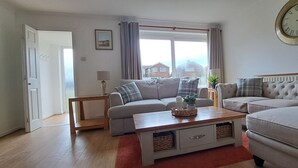 A living room with two sofas, a coffee table, and a clock on the wall. - Generous 3 bed in the heart of the village (Sawtry)