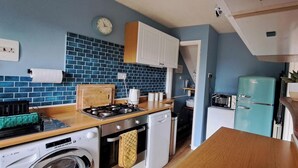A compact kitchen with a gas stove, a washing machine, a toaster, and a vintage blue refrigerator. - Generous 3 bed in the heart of the village (Sawtry)