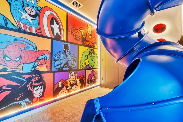 A room with a vibrant comic book mural on the wall and a blue chair in the foreground.