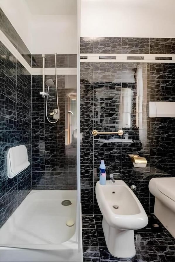 A bathroom with a glass-enclosed shower, a bidet, and a toilet. - Garden House Fiera Milano (Pero)