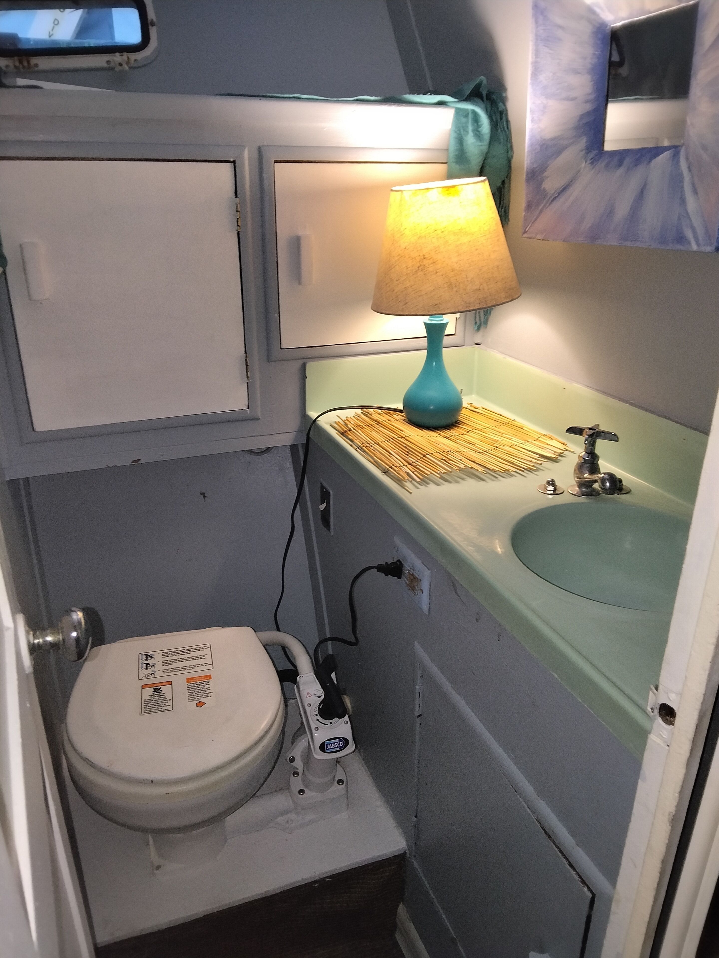 A small bathroom with a toilet, a sink, and a lamp.