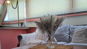 A room with a wooden table, a sofa with cushions, a hanging light fixture, and a window with blinds. - Authentic 40' Hatteras Yacht 
Budget Keys Living & Ocean Views  (Key West)