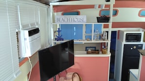 A beach-themed room with a flat-screen TV, a small kitchen area, a welcome sign, and a decorative anchor. - Authentic 40' Hatteras Yacht 
Budget Keys Living & Ocean Views  (Key West)