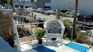 A balcony with a white wicker chair, a blue mat, and a red bench. - Authentic 40' Hatteras Yacht 
Budget Keys Living & Ocean Views  (Key West)