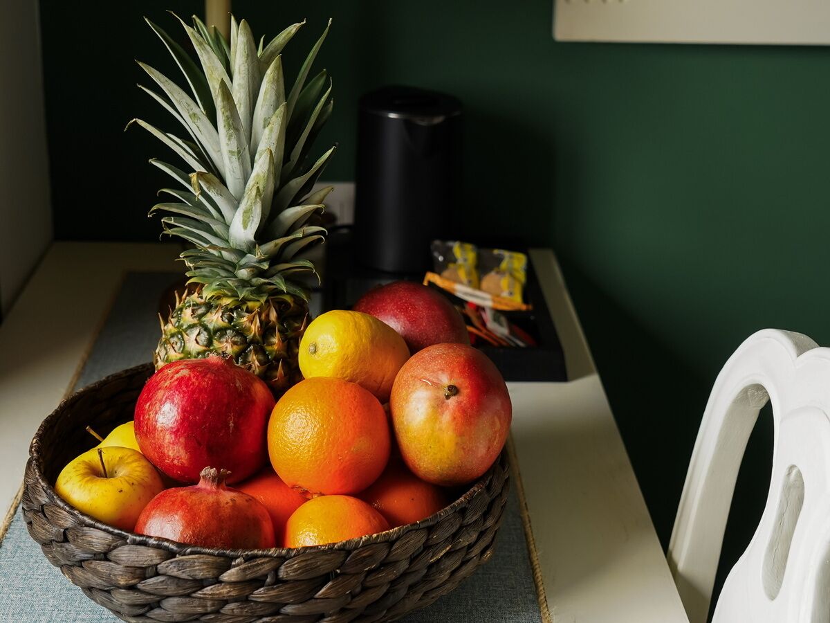 A woven basket filled with fruits and a pineapple on a table.