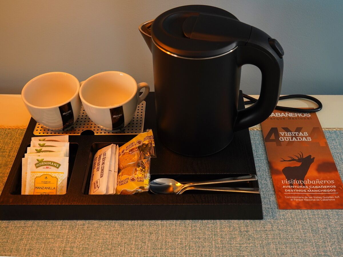 A tray with a black coffee pot, two white cups, a spoon, and some food packets.