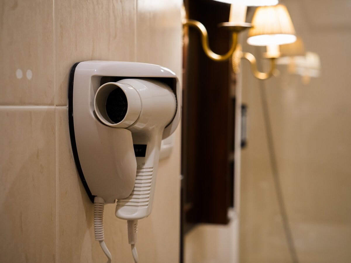 A wall-mounted hairdryer in a bathroom.