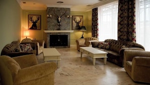 A living room with a fireplace, two sofas, a coffee table, and decorative antlers on the wall. - NUEVO HOTEL PARQUE CABAÑEROS (Horcajo de los Montes)