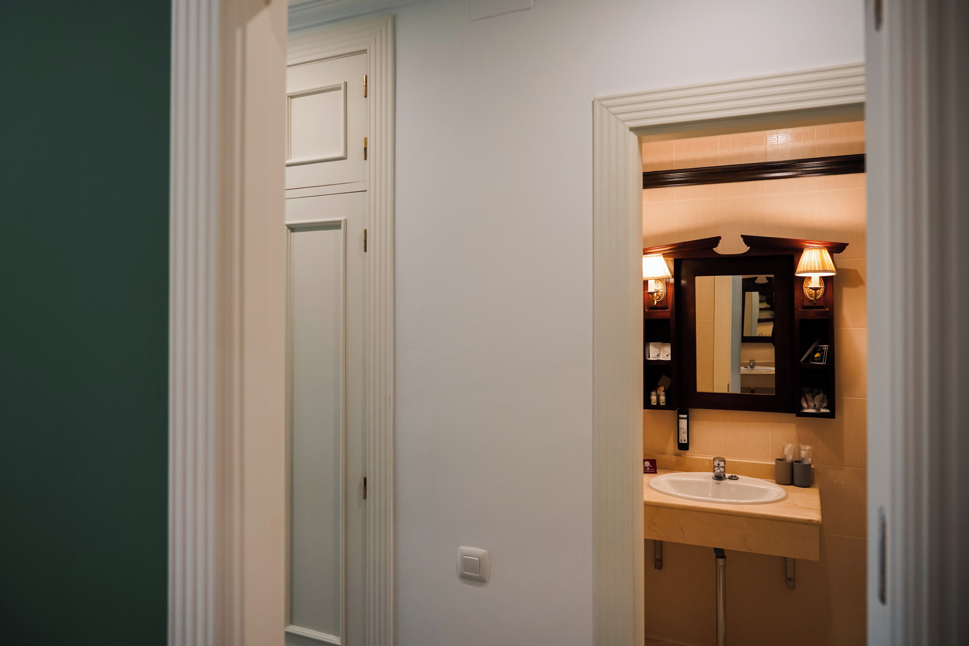 Een badkamer met een witte wastafel, spiegel en twee wandlampen.