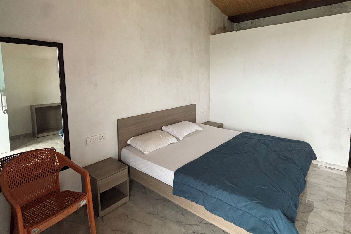 Ein Schlafzimmer mit einem Bett, einem Sessel, einem Nachttisch, einem Deckenventilator und einem Spiegel.