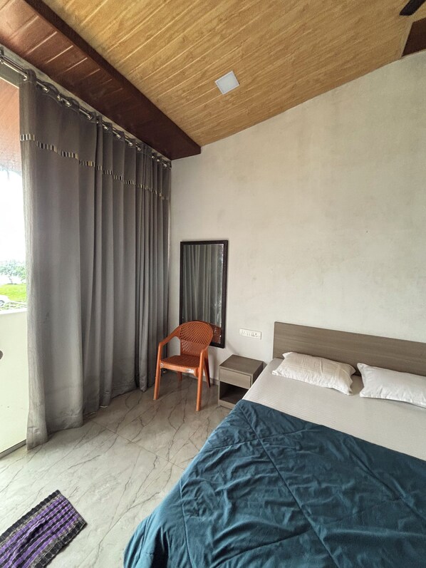Une chambre à coucher avec un lit, une chaise, une table de chevet et une fenêtre avec des rideaux.