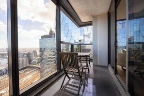 A modern room with large windows offering a city view, a wooden chair, and a table.
