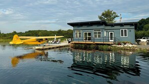 A small dock with a yellow airplane and a blue building with windows and a door.