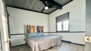 A bedroom with a bed, a window, and skis leaning against the wall.