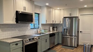 A modern kitchen with white cabinets, stainless steel appliances, and a wooden floor. - Beautiful 2-bedroom water view house in Annapolis (Annapolis)