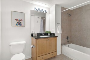 A modern bathroom with a wooden vanity, a white toilet, a sink, and a bathtub.