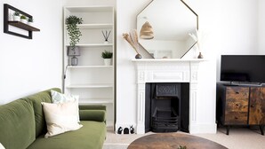 A modern living room with a green sofa, white shelving, a fireplace, and a TV. - Pass the Keys | Poets' Corner Stylish Apartment | Station Location (Hove)
