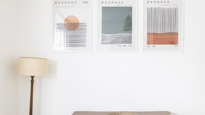 Three framed artworks titled 'BAUHAUS AUSSTELLUNG' from 1923, a lamp, and a woven basket on a table. - Pass the Keys | Poets' Corner Stylish Apartment | Station Location (Hove)