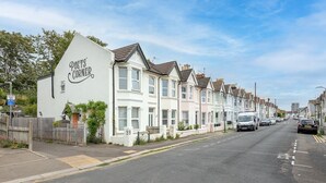 A row of terraced houses with a white building labeled "POET'S CORNER" on the left. - Pass the Keys | Poets' Corner Stylish Apartment | Station Location (Hove)