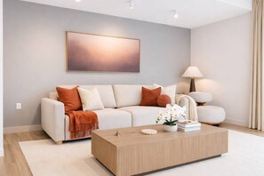 Un salon moderne avec un canapé, une table basse et une lampe.