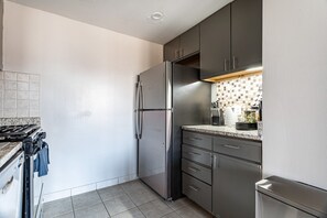 A compact kitchen with a built-in stove, a refrigerator, and a microwave.