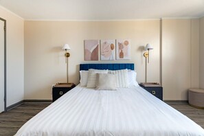 Une chambre d’hôtel avec un grand lit, deux tables de chevet et des œuvres d’art murales.
