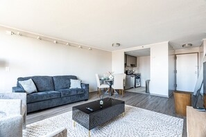 A modern living room with a sofa, coffee table, and a dining area with chairs.