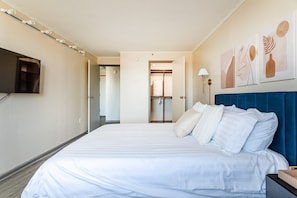 Une chambre d’hôtel avec un grand lit, un téléviseur fixé au mur et des œuvres d’art accrochées au mur.