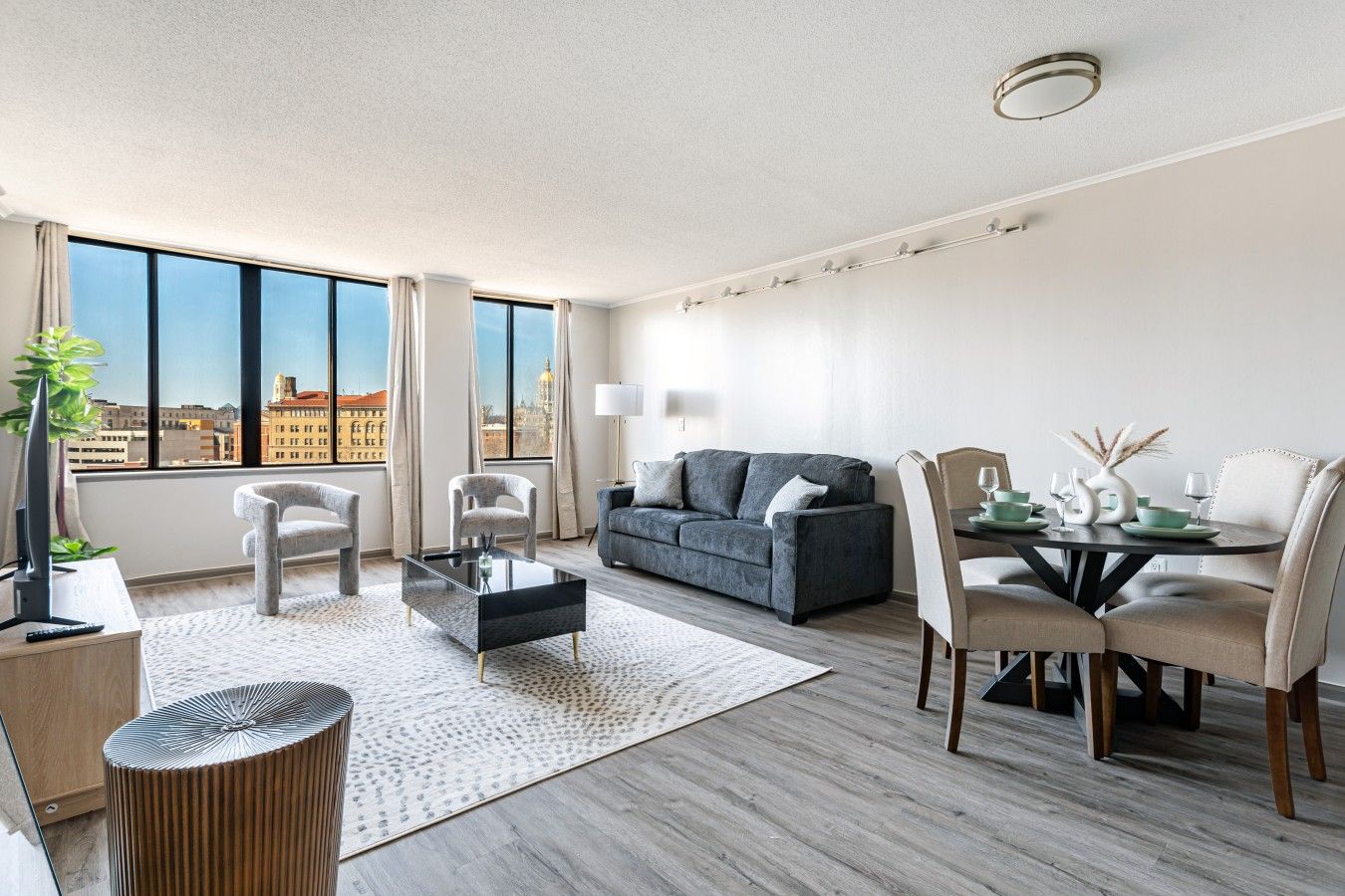 A modern living room with a sofa, chairs, a coffee table, and a dining area with a table and chairs.